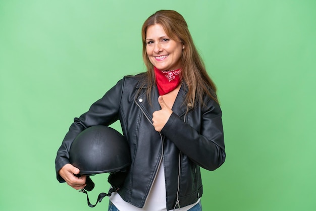 Mujer caucásica de mediana edad con un casco de motocicleta sobre un fondo aislado dando un gesto de pulgar hacia arriba