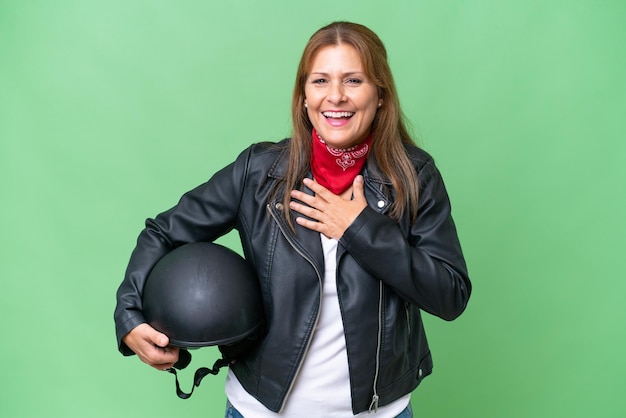 Mujer caucásica de mediana edad con un casco de motocicleta sobre un fondo aislado sonriendo mucho