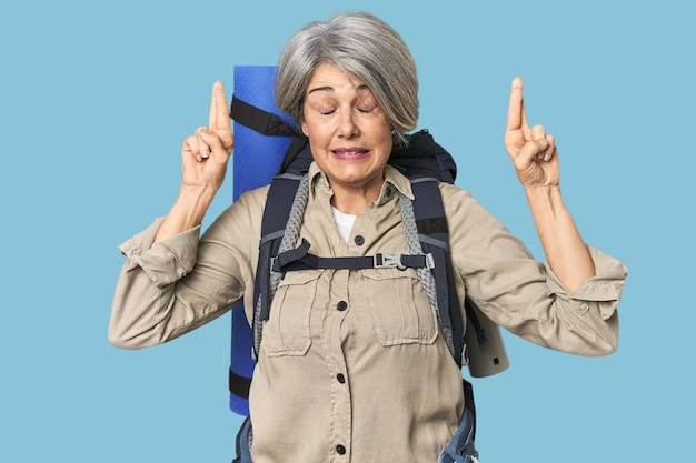 Mujer caucásica de mediana edad con equipo de senderismo cruzando los dedos por tener suerte