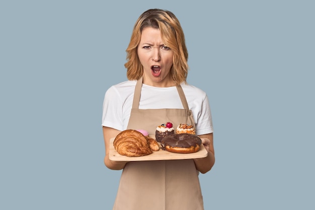 Mujer caucásica de mediana edad panadera con pasteles gritando muy enojada y agresiva