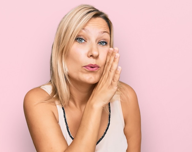 Foto mujer caucásica de mediana edad con ropa informal con las manos en la boca diciendo rumores secretos susurrando conversaciones maliciosas