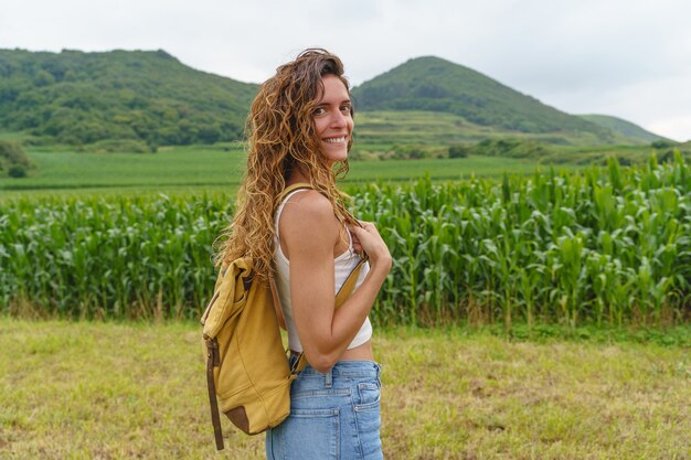 Mujer caucásica en medio del campo de maíz. Vista horizontal del viajero mochilero en las montañas.