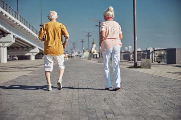 Mujer caucásica de pelo gris y un hombre caminando por la mañana