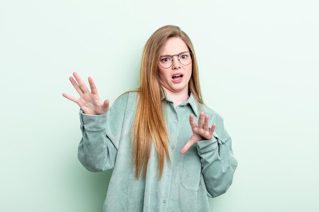 Mujer caucásica de pelo rojo que se siente aterrorizada retrocediendo y gritando de horror y pánico reaccionando a una pesadilla