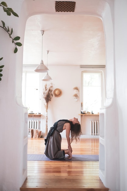 Mujer caucásica practicando clases de yoga haciendo ushtrasana o pose de camello