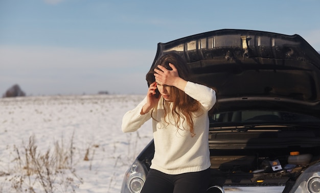 Mujer caucásica que tiene un problema con el coche en un viaje por carretera