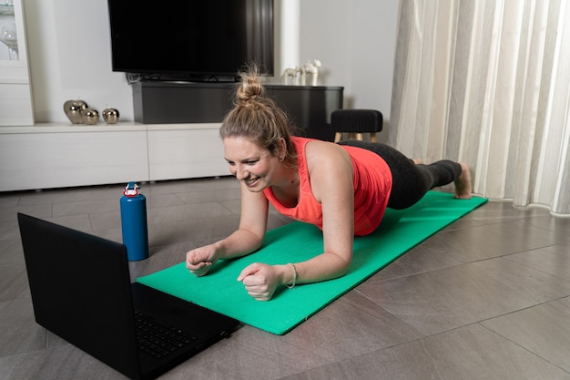 Mujer caucásica rubia y con curvas practicando deporte en casa de forma tranquila y sonriente.