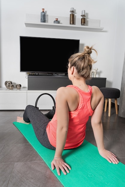 Mujer caucásica rubia y con curvas practicando deporte en casa de forma tranquila y sonriente.