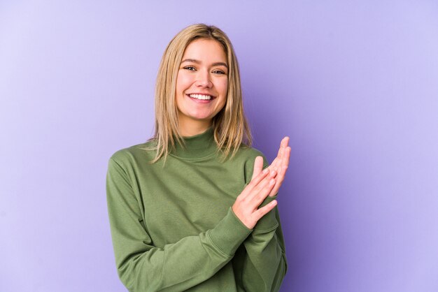 La mujer caucásica rubia joven aisló sentirse enérgico y cómodo, frotándose las manos confiadas.