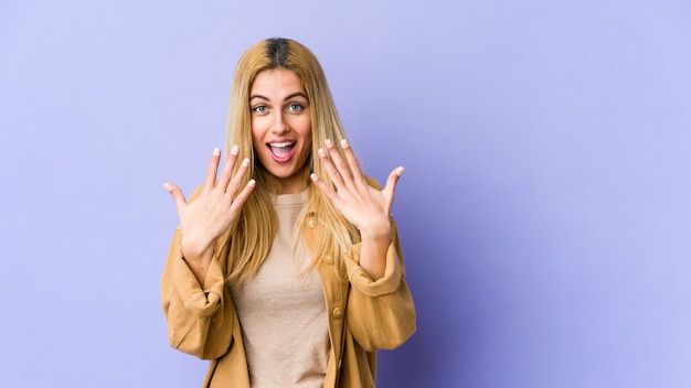 Mujer caucásica rubia joven que muestra el número diez con las manos.