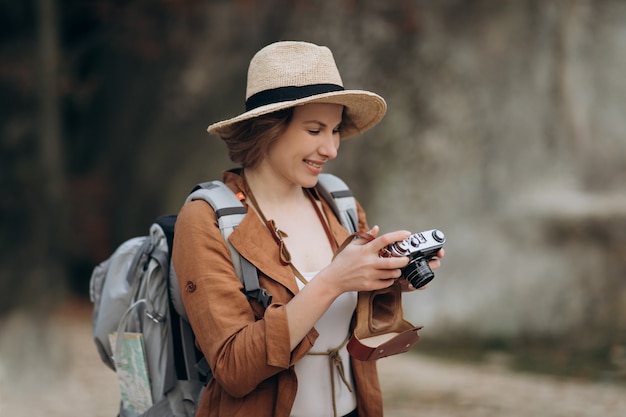 Mujer caucásica sana activa tomando fotos con una cámara de película vintage en un bosque de rocas