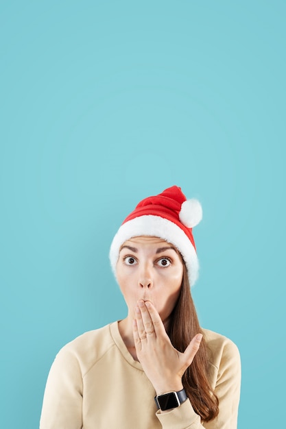 La mujer caucásica con el sombrero de santa sorprendió el retrato. Fondo azul