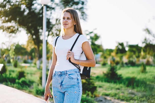 Mujer caucásica sonriente descansando en el ocio de verano y paseando por la calle en un entorno urbano