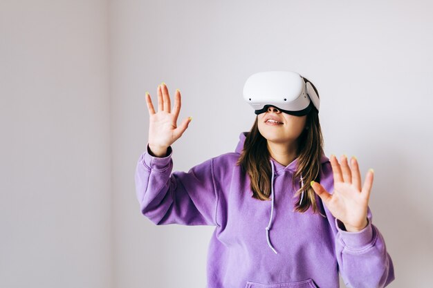 Mujer caucásica sonriente joven que usa el casco de Vr, gesticulando y mirando hacia arriba en la realidad virtual.