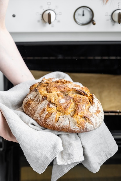 Mujer caucásica sosteniendo pan fresco del horno para hornear pan casero