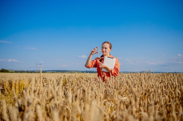 Mujer caucásica tecnólogo agrónomo con tablet PC en el campo