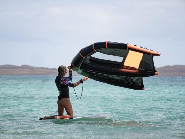 mujer caucásica, tenencia, wingfoil, en el agua