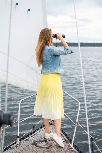 Mujer caucásica viendo binoculares en el velero