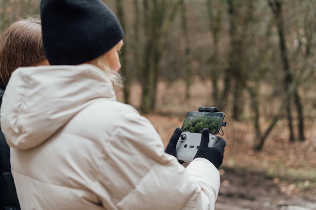 Mujer caucásica volando drone aéreo en bosque de otoño.