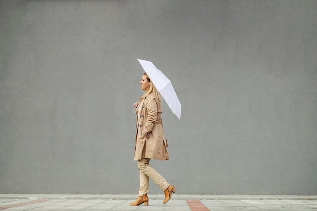 Una mujer causal inteligente en la colección de otoño caminando por la calle del centro de la ciudad