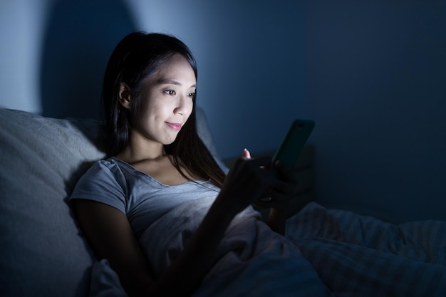 Mujer con celular en la cama