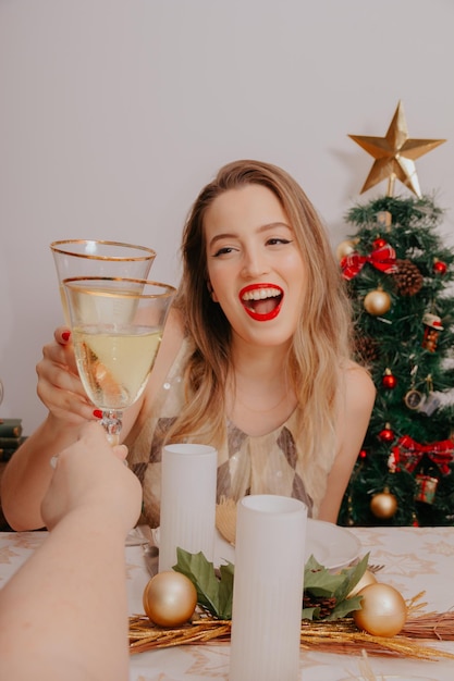 Mujer en la cena de Navidad con vino espumoso y regalos