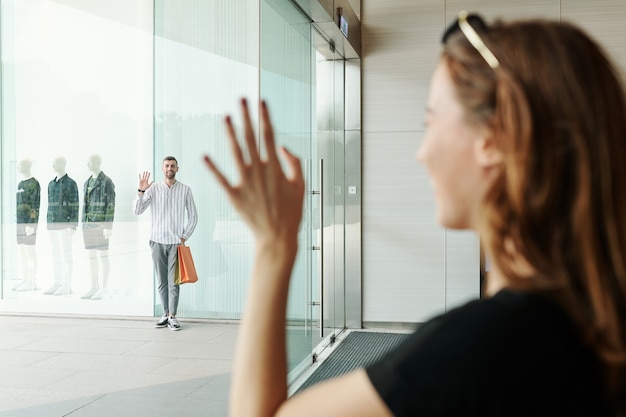 Mujer en centro comercial saludando a novio