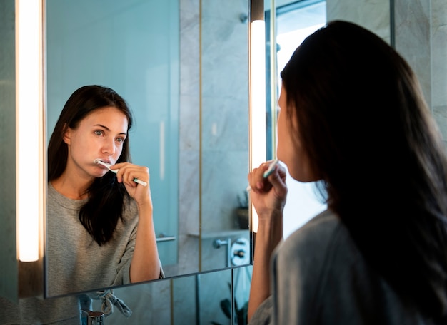 Mujer cepillándose los dientes por la mañana