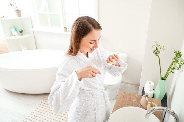 Mujer cepillarse los dientes en el baño.