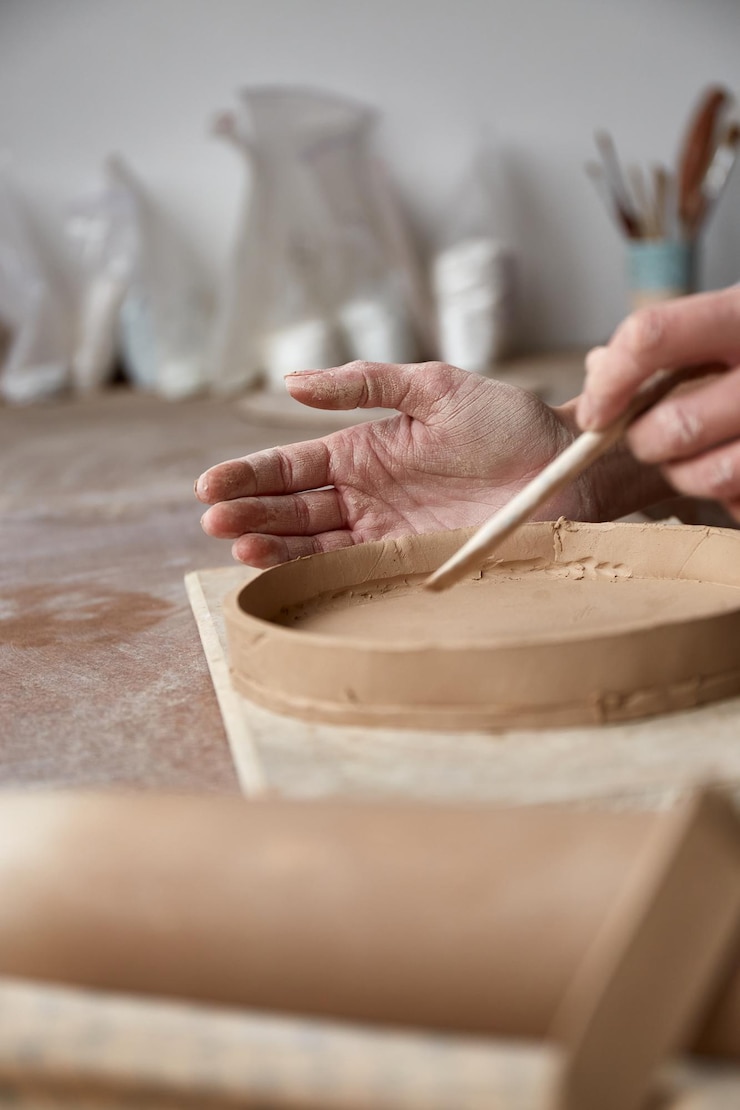 Foto mujer ceramista trabajando en taller de cerámica ceramistas manos sucias de arcilla proceso de creación de cerámica maestro ceramista trabaja en su estudio