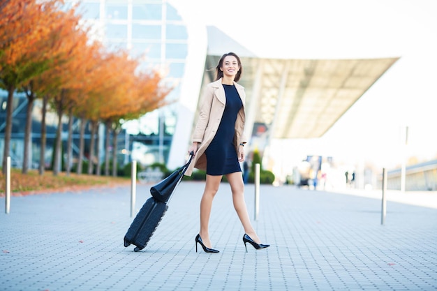Mujer cerca del aeropuerto con una maleta se va de viaje