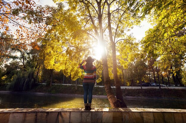 Mujer cerca del árbol en el parque de otoño