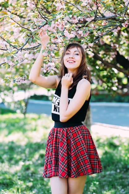 Mujer cerca del floreciente árbol de primavera, libre feliz disfrutando de la frescura y la belleza de la naturaleza. Mujer cerca de sakura, flor de cerezo.