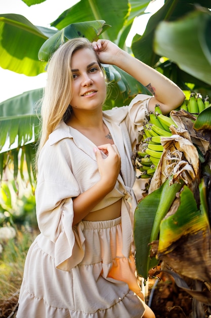 Mujer cerca de la gran hoja verde del árbol de plátano en la naturaleza en el parque. Plantas tropicales