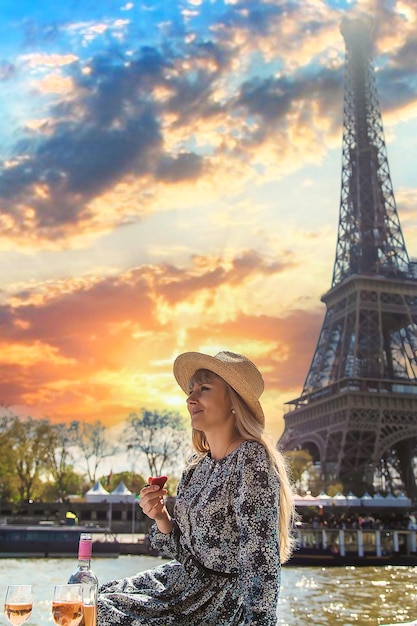 Una mujer cerca de la Torre Eiffel bebe vino Enfoque selectivo