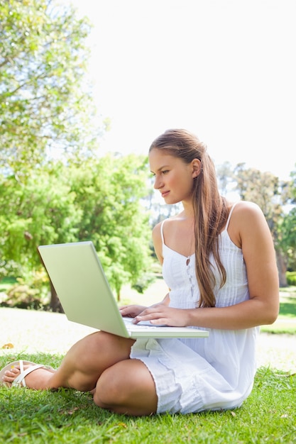 Mujer en el césped con su computadora portátil