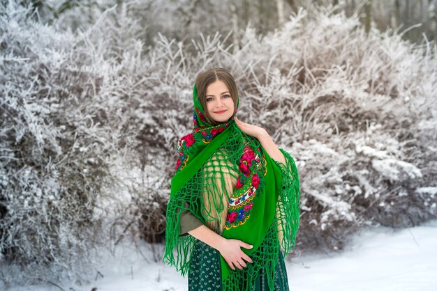 Mujer con un chal verde en bosque de invierno.