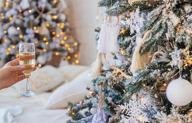 Mujer con champán en sus manos cerca del árbol de Navidad Enfoque selectivo