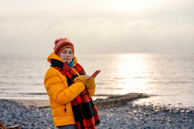 Mujer con chaqueta amarilla brillante caminando sola en la playa en el frío día de invierno Concepto de estilo de vida de viaje