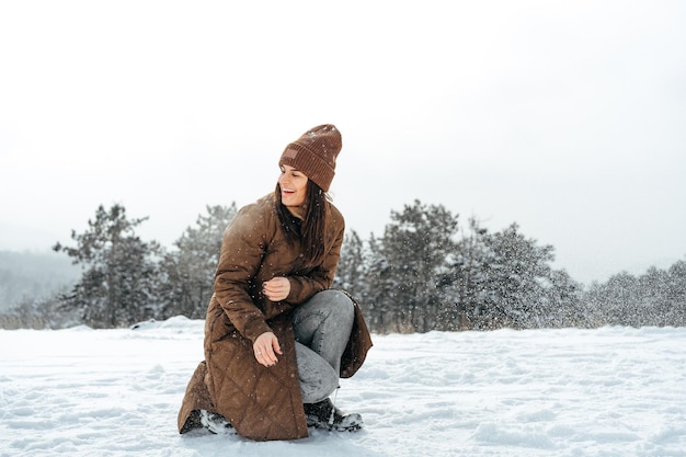 Mujer con chaqueta cálida de invierno caminando en un bosque nevado de invierno