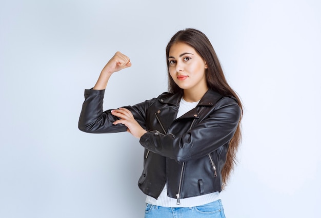 mujer con chaqueta de cuero mostrando los músculos de su brazo.