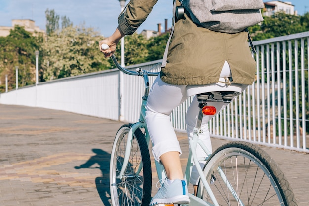 Mujer en chaqueta y jeans monta una bicicleta