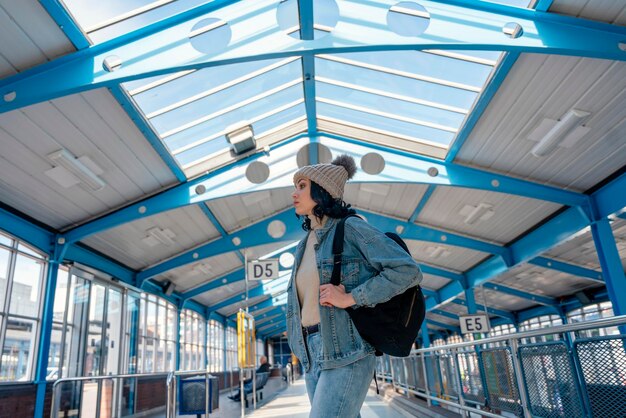 una mujer con una chaqueta de mezclilla está hablando por teléfono y esperando un autobús de tranvía Foto de estilo de vida