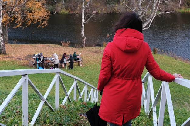 Una mujer con una chaqueta roja y un paraguas pasea por el parque de otoño