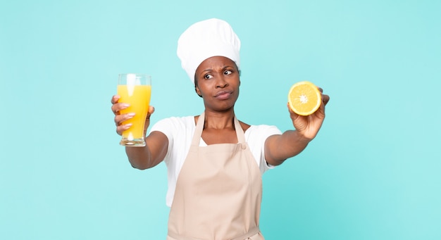 Mujer chef adulta afroamericana negra. concepto de jugo de naranja