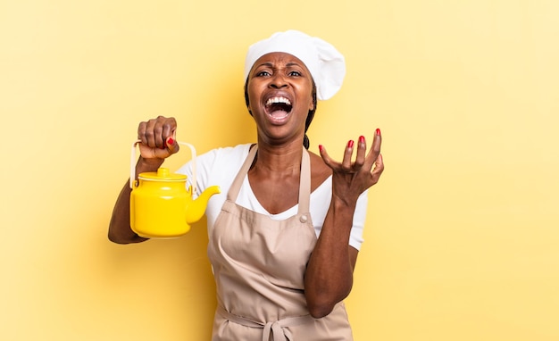 Mujer chef afro negra que parece desesperada y frustrada, estresada, infeliz y molesta, gritando y gritando. concepto de tetera