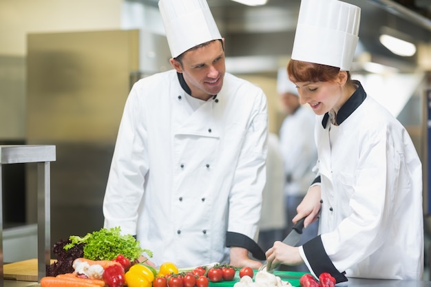 Mujer chef cortar verduras con colega