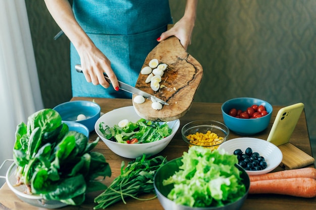 Foto una mujer chef irreconocible prepara una ensalada y pone los ingredientes en un cuenco grande