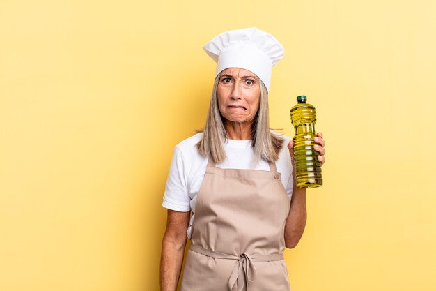 Mujer chef de mediana edad que mira perpleja y confundida, mordiendo el labio con un gesto nervioso, sin saber la respuesta al problema