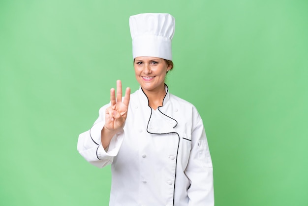 Mujer chef de mediana edad sobre un fondo aislado feliz y contando tres con los dedos